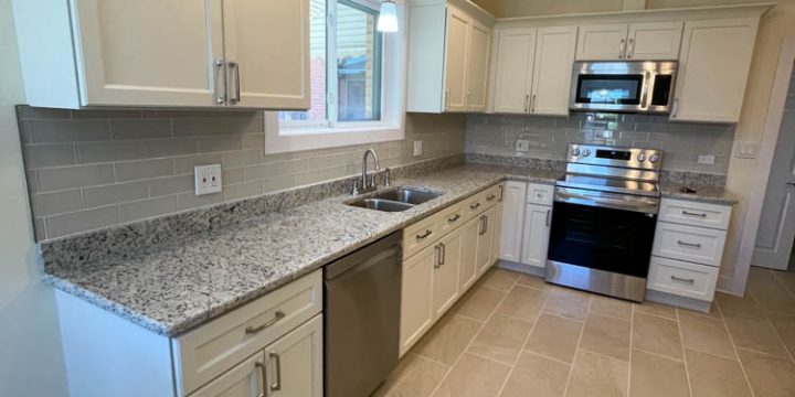 Modern kitchen featuring white shaker cabinets, speckled granite countertops, stainless steel dishwasher and range, and gray subway tile backsplash. Includes recessed lighting, pendant light, and ceiling fan — creating a clean, functional, and inviting space.