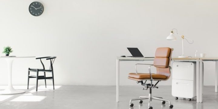 Sleek, minimalist home office featuring a white desk with laptop, brown leather ergonomic chair, white filing cabinet, and black wire-frame side chair. Includes wall clock, small plant, and natural light — ideal for productivity and modern remote work.